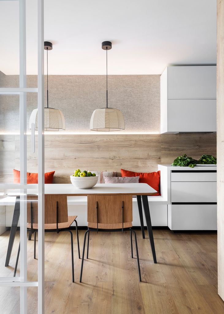 Cocina con muebles blancos y paredes con acabado madera. 