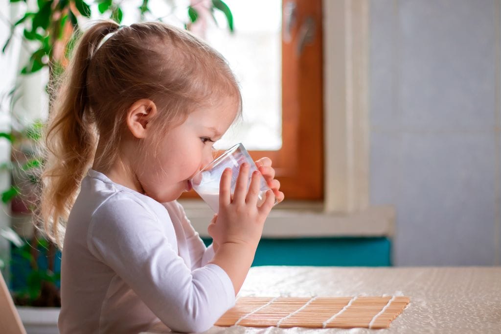 Niña bebiendo un vaso de leche
