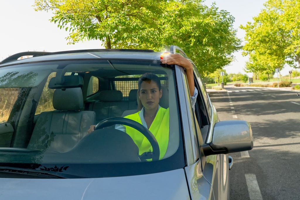 Mujer con el coche averiado colocando la baliza v16