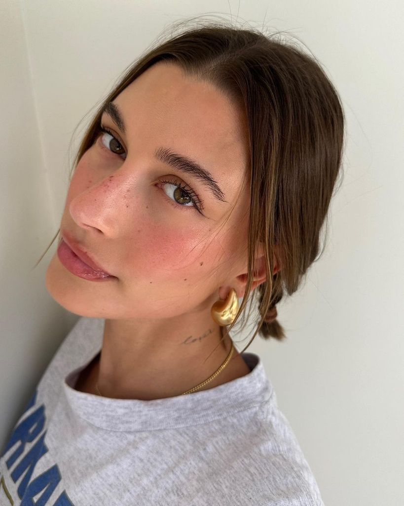 Primer plano de Hailey Bieber con maquillaje de pecas y trenzas