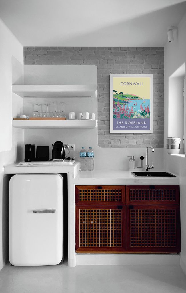 Estilo ‘vintage’ en una pequeña cocina con mobiliario de madera y un póster que reproduce un paisaje costero