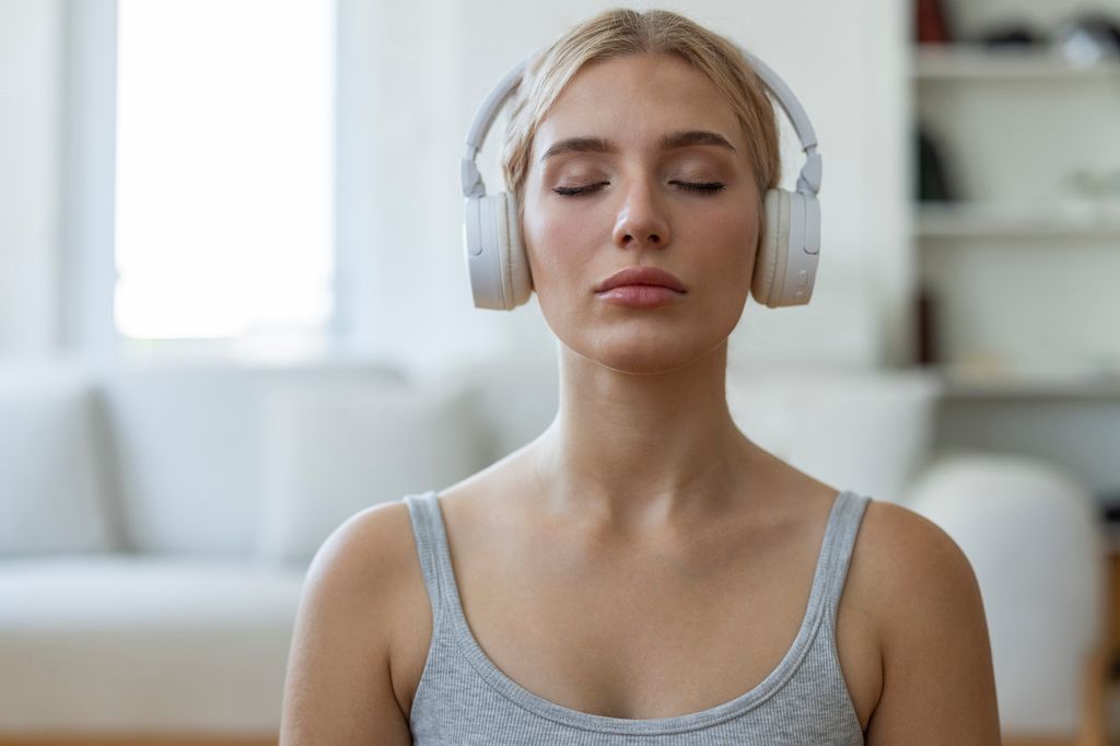 Mujer respirando escuchando meditacion con auriculares
