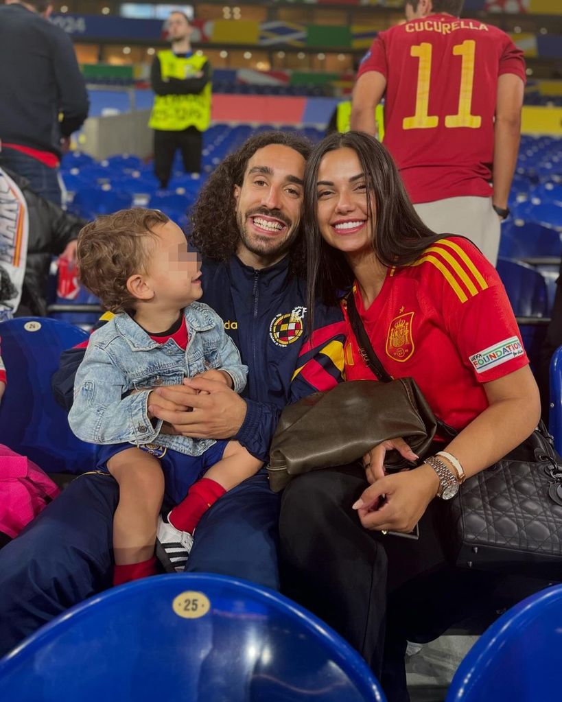 Pareja con niño en estadio, ella en camiseta España, él en chaqueta Barça.