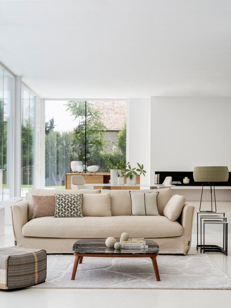 Salón con sofá beis y mesa de centro de madera y mármol