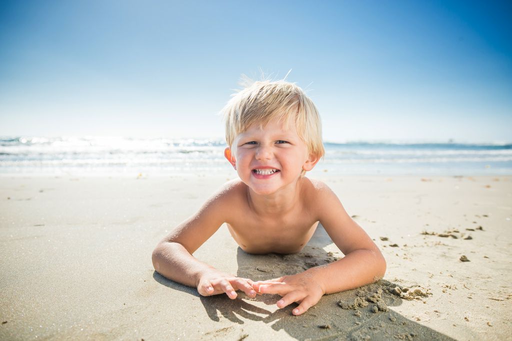 Niño tumbado en la arena de la playa