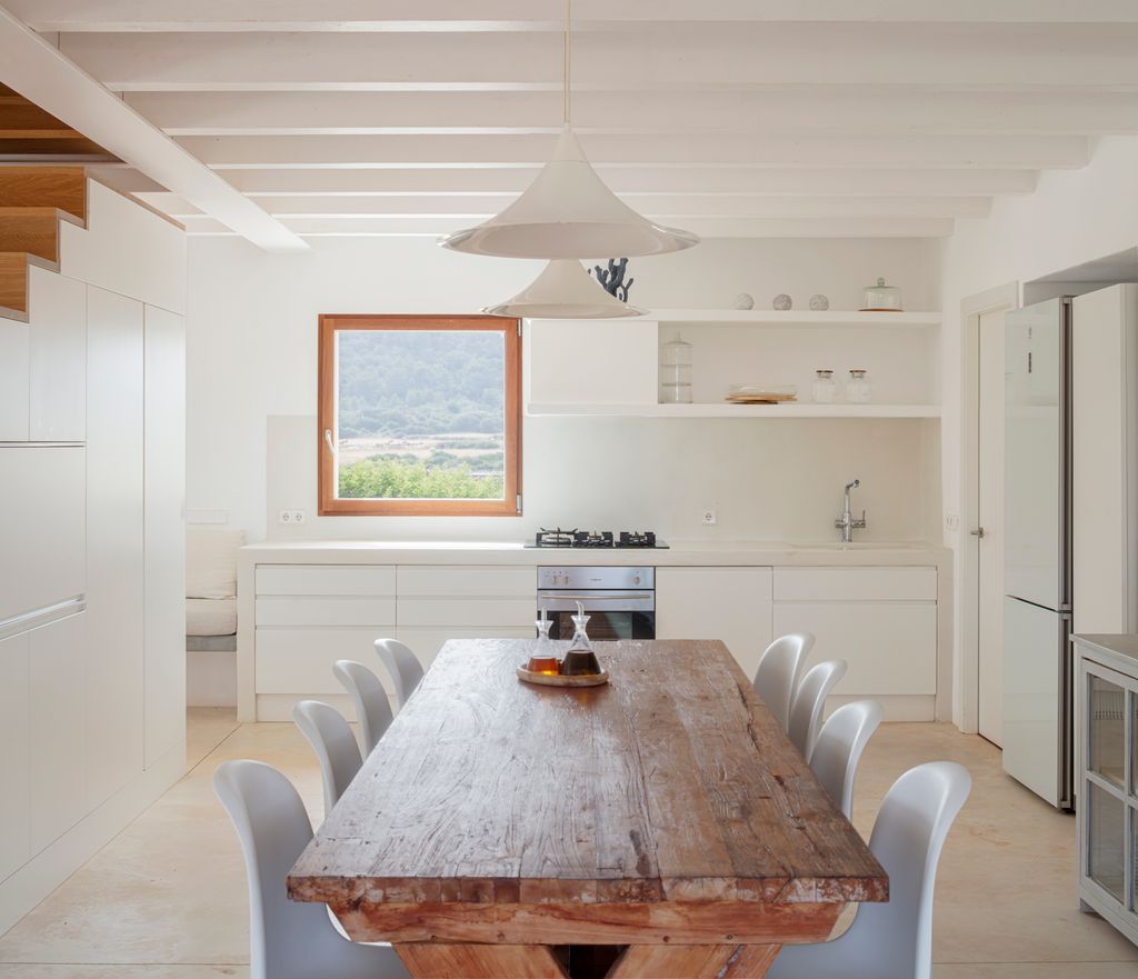 Cocina con muebles blancos y mesa de comedor de madera