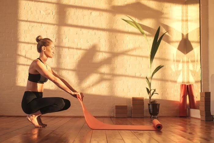 mujer extendiendo una esterilla para hacer pilates