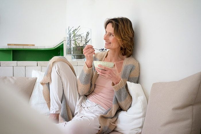 mujer comiendo en el sofá