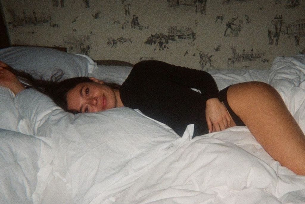 Plano medio de Anna Castillo posando tumbada en una cama