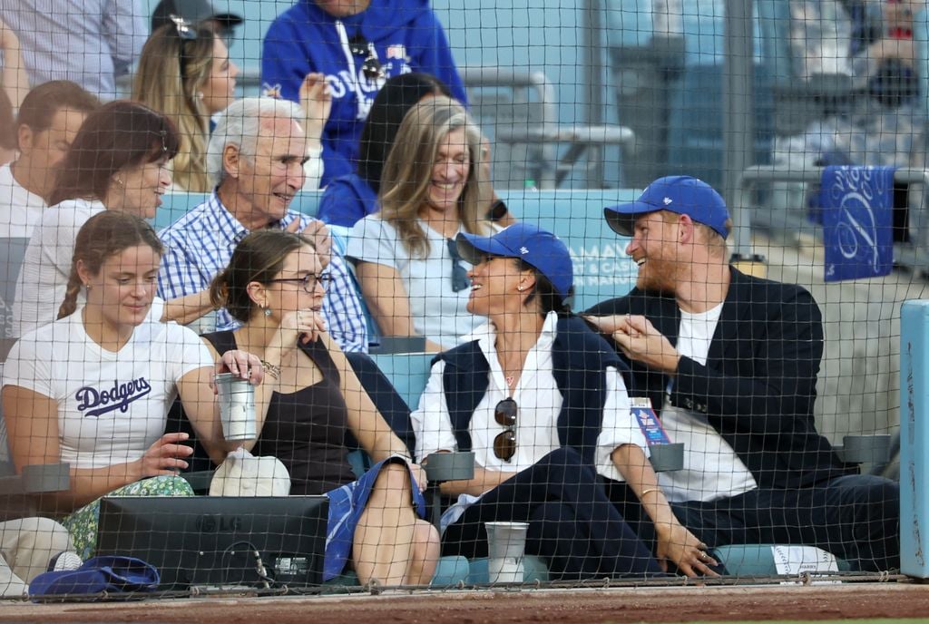 Harry y Meghan charlan amistosamente con Sandy Koufax, leyenda del béisbol norteamericano, durante el partido