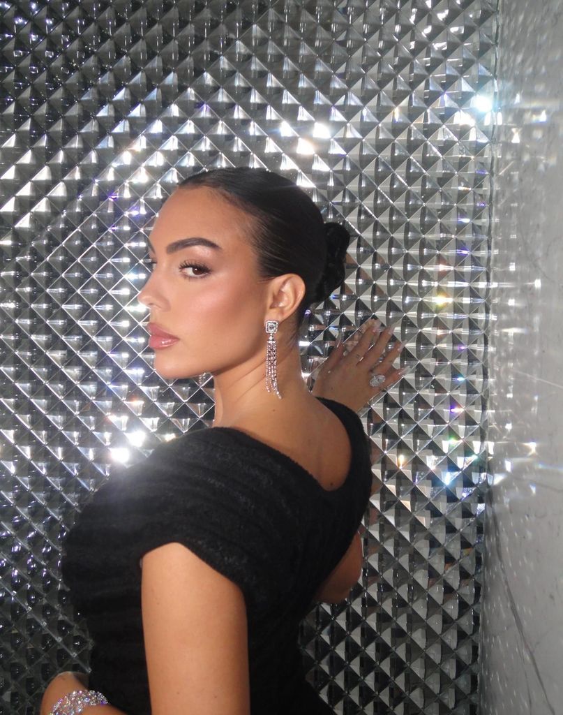 Georgina Rodríguez con vestido negro, pendientes de diamantes sobre pared metalizada