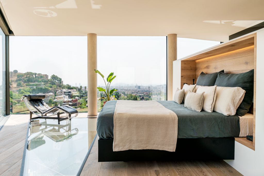Dormitorio con una gran cristalera con vistas al verde paisaje