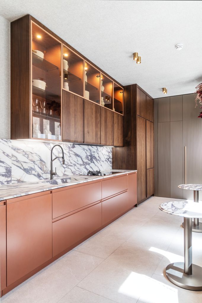 Cocina con muebles de madera y cobre y encimera de porcelánico efecto mármol