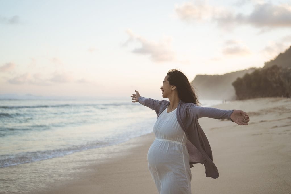 Mujer embarazada feliz en la playa