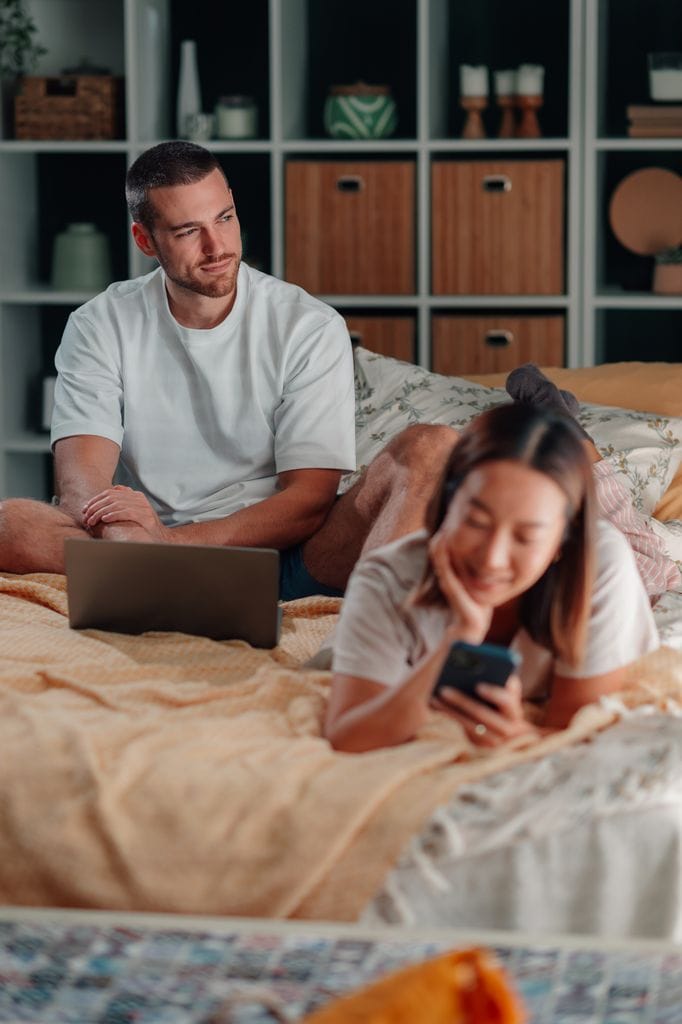 chico ordenador chica movil cama