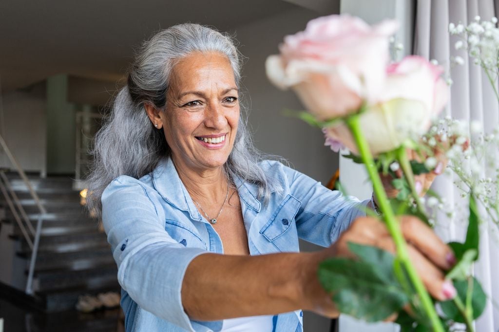 Mujer madura clocando flores en un florero