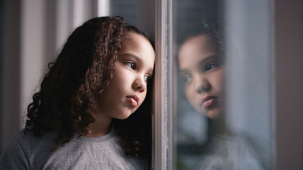 Niña deprimida mirando por la ventana