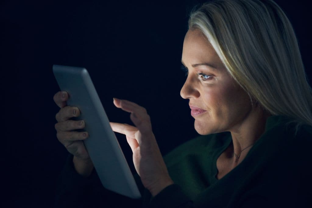 Mujer madura consultando su tableta por la noche