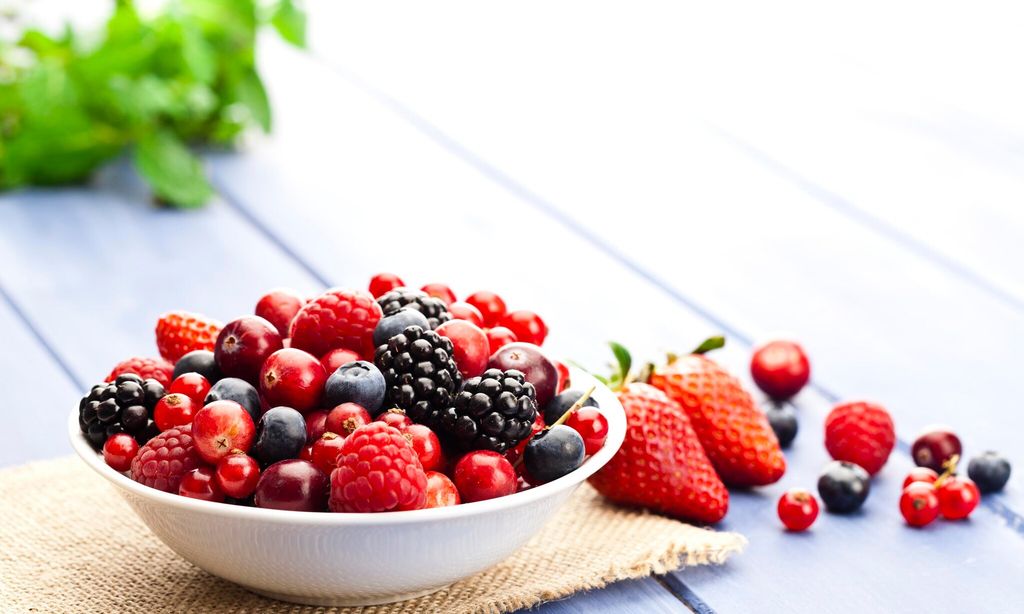 Plato blanco con arandanos, fresas, moras y frambuesas.