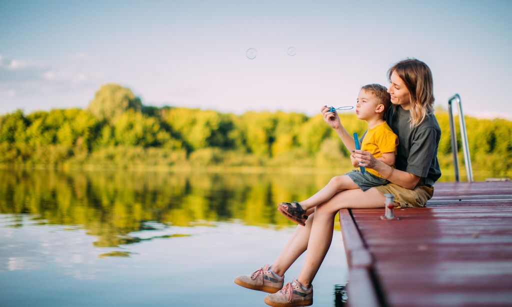 madre con hijo jugando en un muelle con pompero
