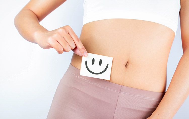 Mujer que demuestra con un dibujo de una cara sonriente que tiene buena salud intestinal