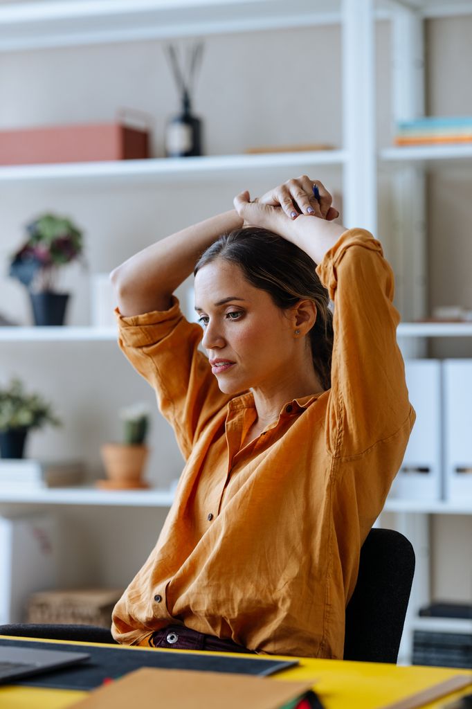 Mujer frente al escritorio intentando relajarse