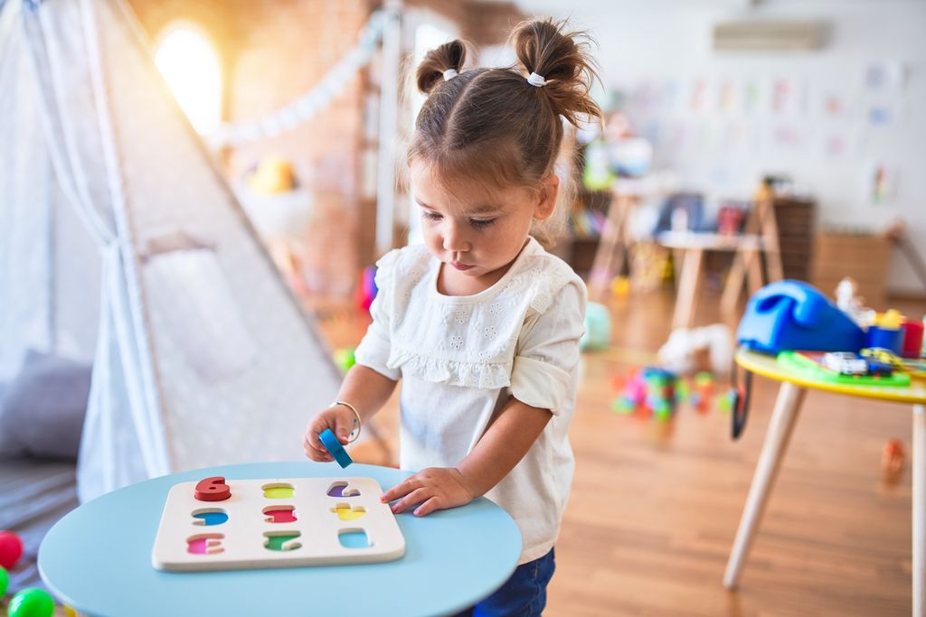 Niña jugando en su habitación llena de juguetes