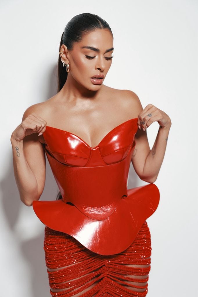 El vestido, construido con un corset en piel roja, acompañado de un peplum, con una falda corte lápiz, bordada a mano con miles de cuentas unidas una a una.