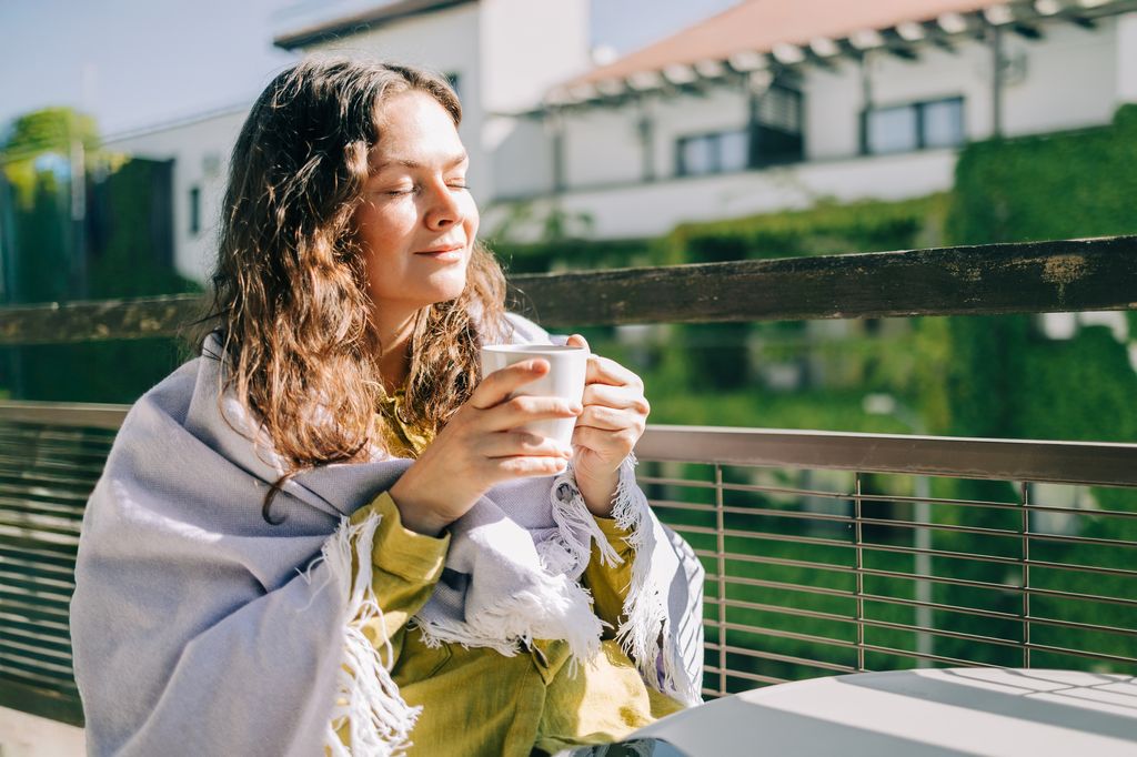 Mujer en una terraza tomando una infusión con una expresión relajada