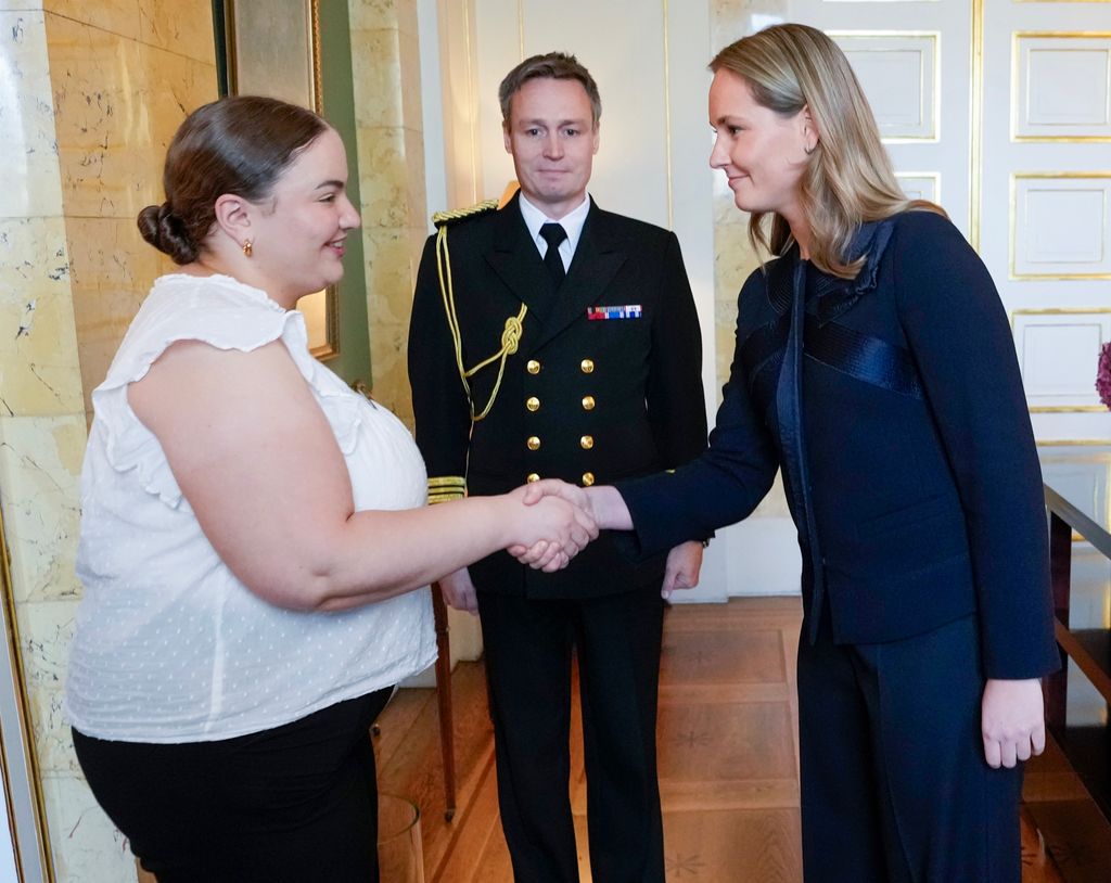 La princesa Ingrid de Noruega con traje de chaqueta azul marino recibe a los representantes de la Operación Dagsverk en la audiencia en el castillo