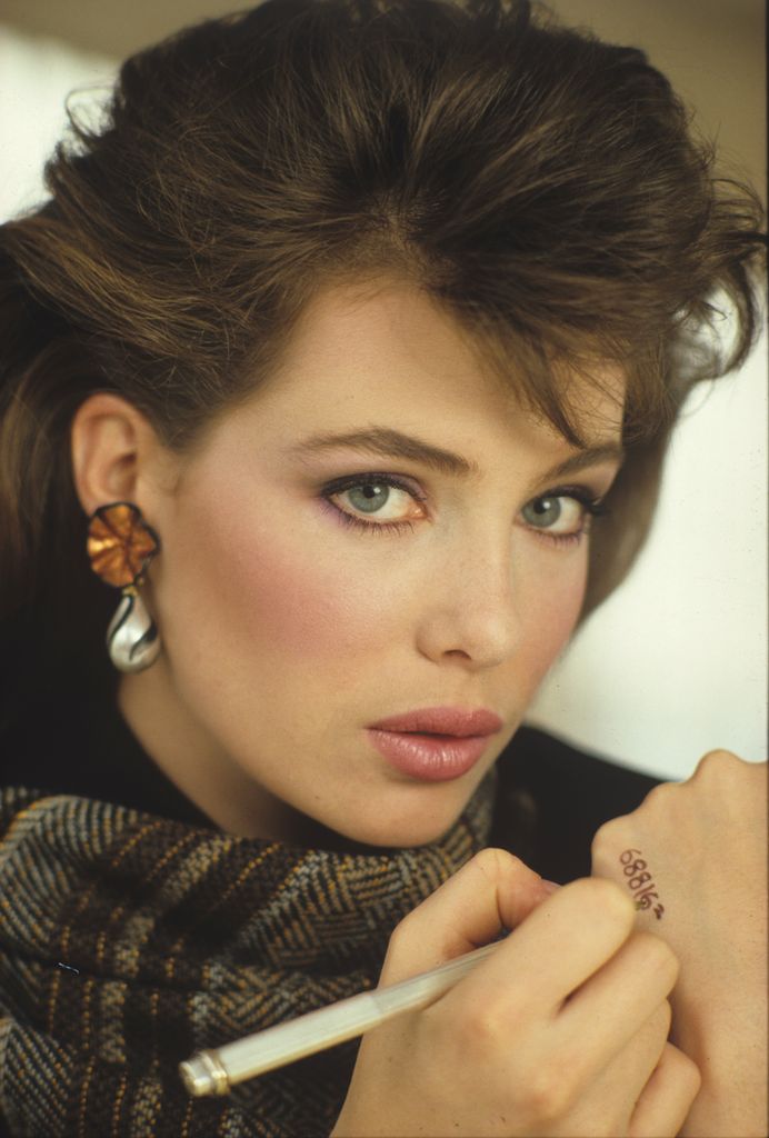 Retrato en primer plano de la actriz y modelo estadounidense Kelly LeBrock mientras se escribe un número de teléfono en la mano durante una sesión fotográfica para una revista, a principios de la década de 1980