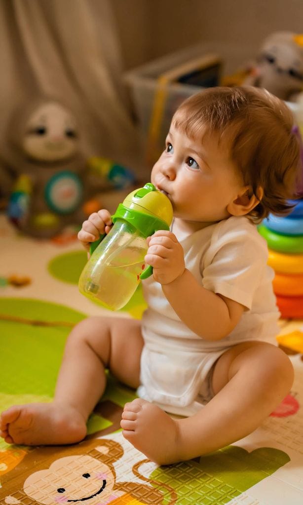 Bebé con vasito con pajita bebiendo agua