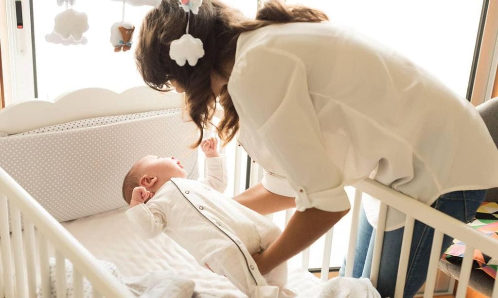 mam poniendo a beb en la cuna para dormir