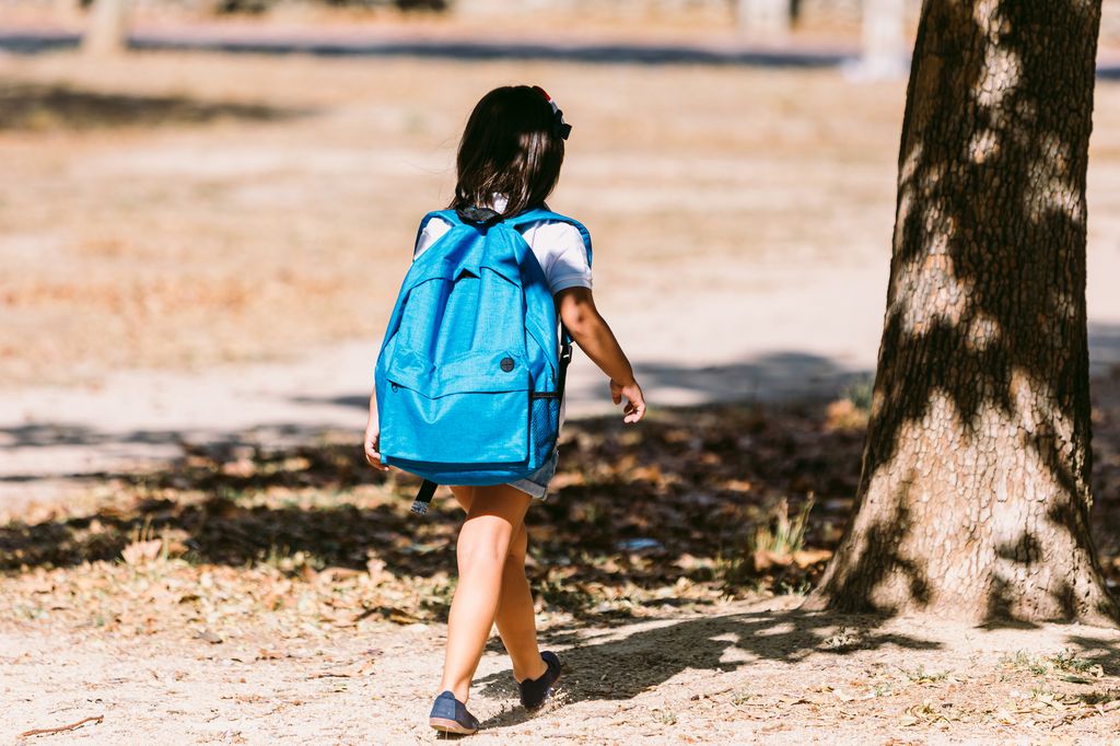 Niña camino del colegio con una mochila azul 
