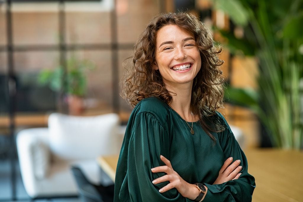 mujer con el pelo rizado sonriente mirando a cámara