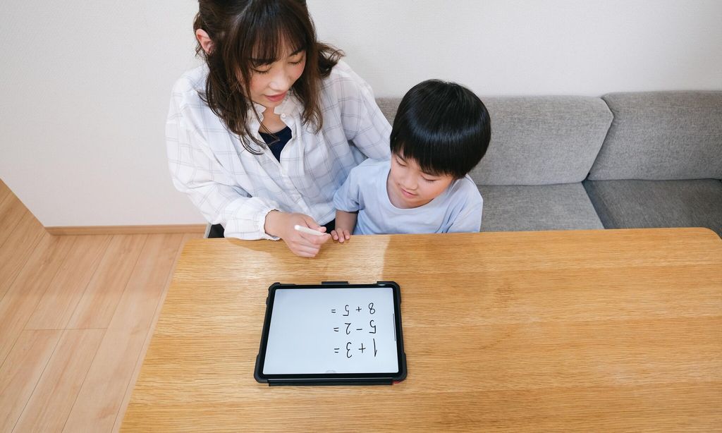 elementary student using tablet pc with mother