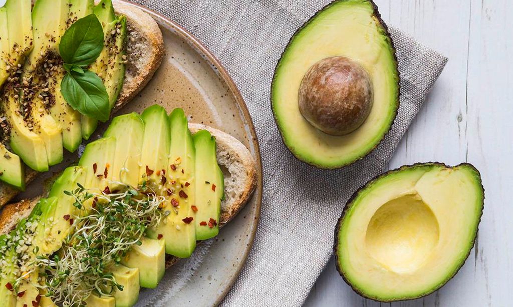 tostadas con rodajas de aguacate hojas de albahaca y condimentos 