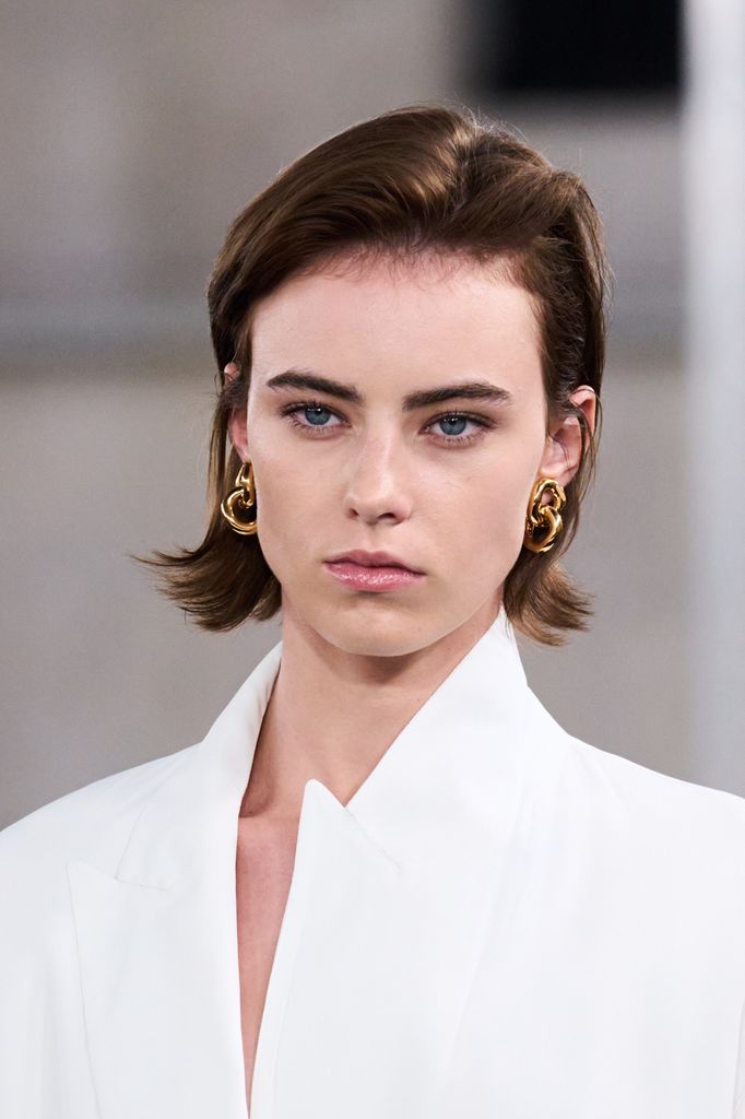 Modelo con estilismo blanco, pendientes dorados y pelo castaño