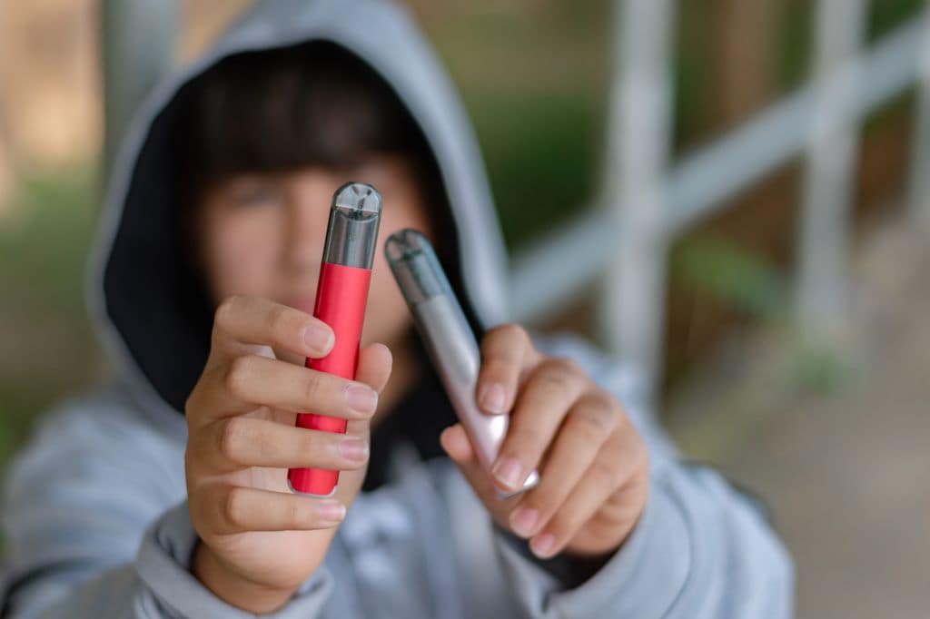 Adolescente con dos vapeadores en la mano