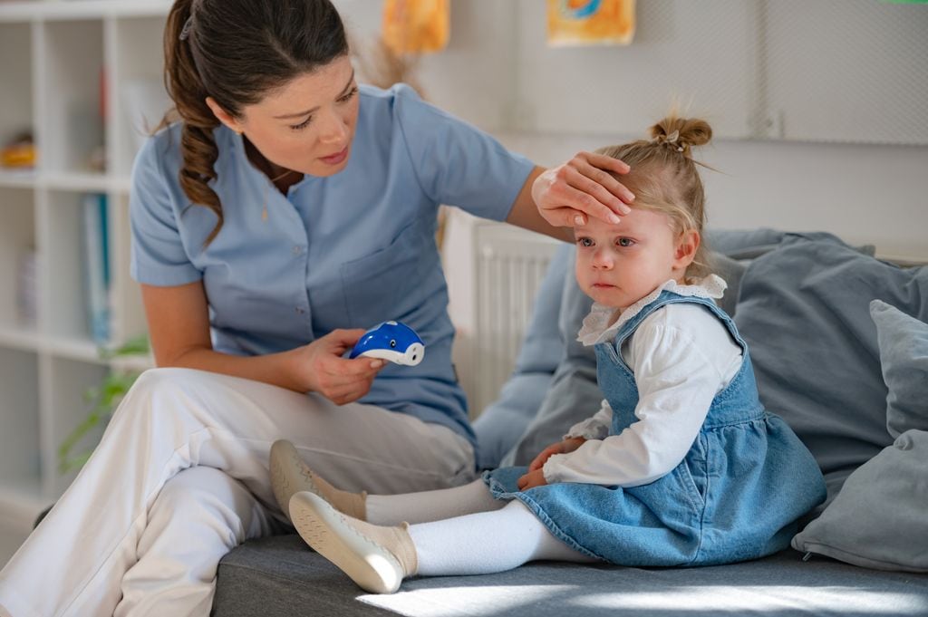 Enfermera tomando la fiebre a una niña pequeña