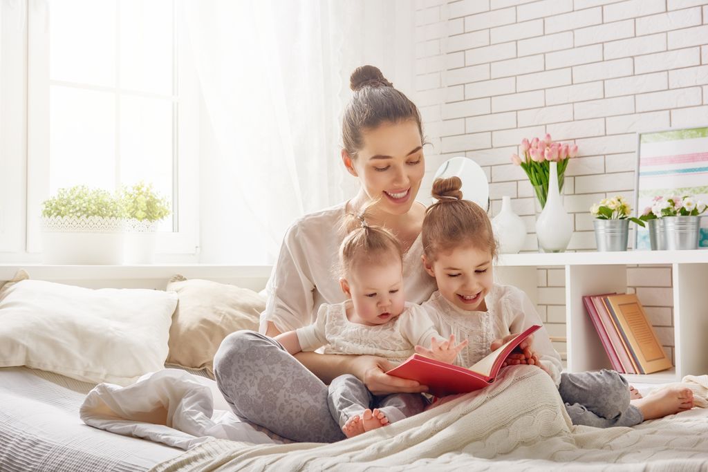 Madre leyendo un libro a sus hijas pequeñas