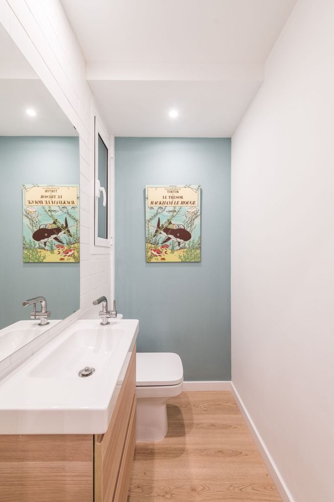 Baño pequeño con pared pintada de azul. 