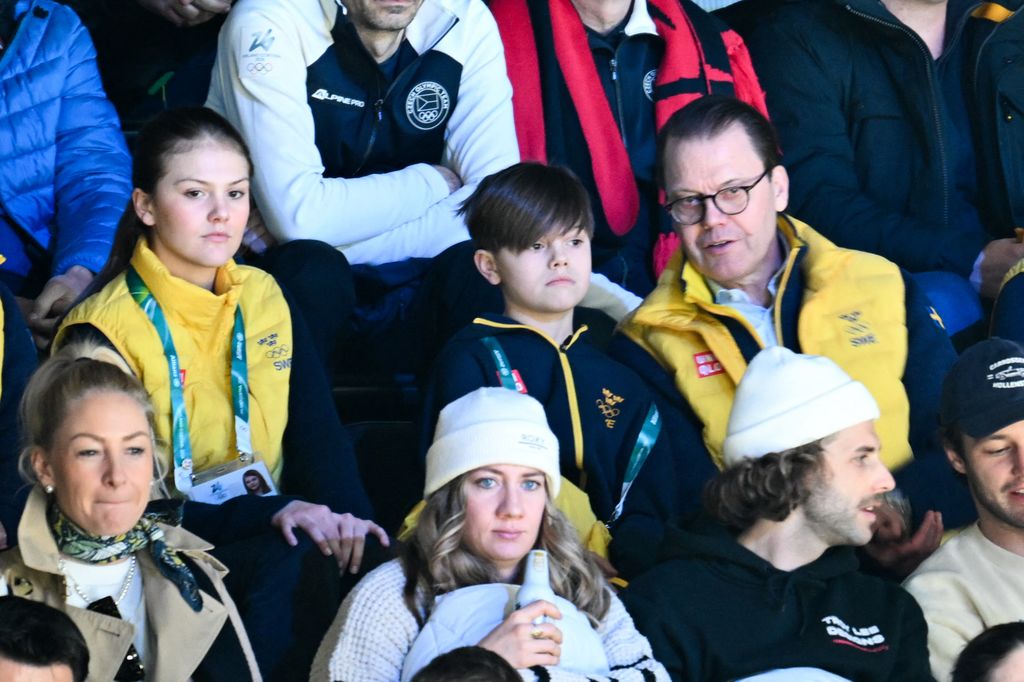 El príncipe Daniel comentando algo del partido de hockey sobre hijo co su hijo