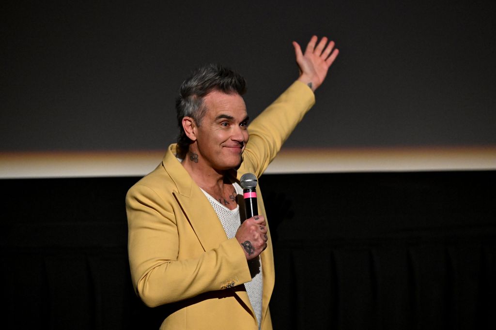 Plano medio de Robbie Williams hablando en el escenario de una premiere 