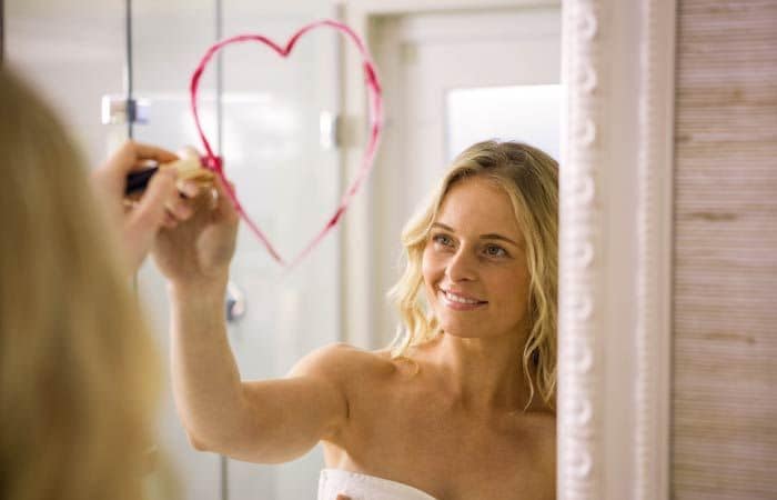 Chica dibujando un corazón en un espejo