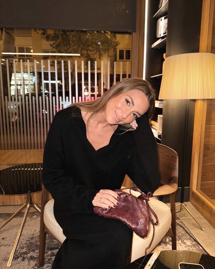 plano medio de Alice Campello posando en un restaurante  con vestido largo negro