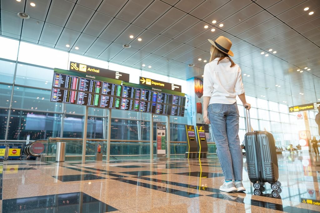 mujer mirando las pantallas del aeropuerto 