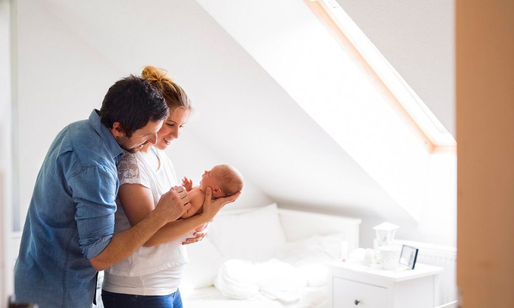 Parents cuddling with little baby at home