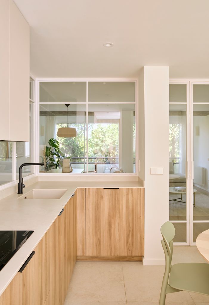 Cocina con muebles de madera separada del salón con cerramiento acristalado