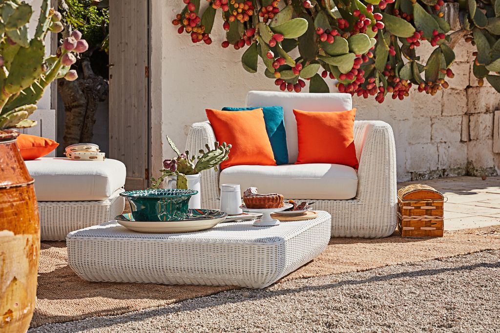 Salón de verano con muebles blancos y cojines naranjas y azul